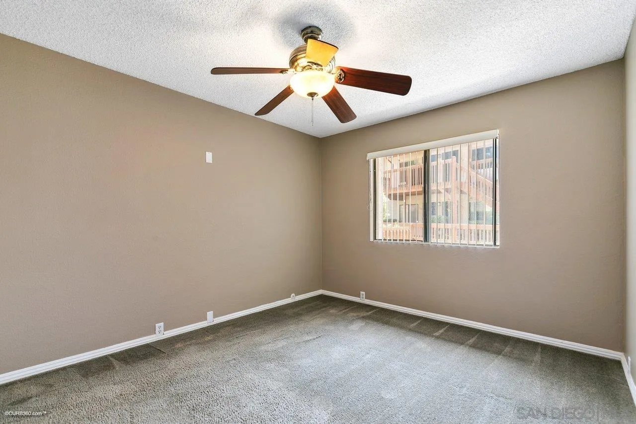 6394 Rancho Mission Road, Unit 106 San Diego, CA 92108 - Photo 10 of 23 an empty room with a window and a ceiling fan