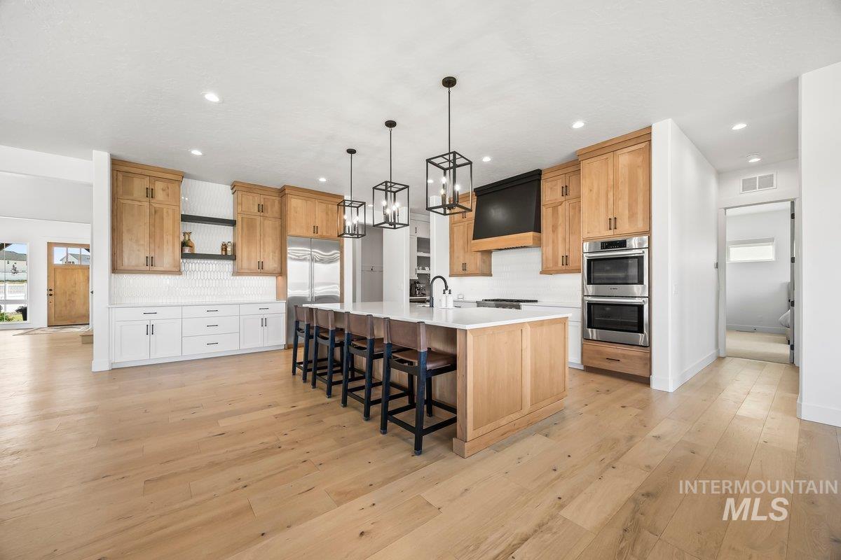 13746 North Ruffed Grouse Way Boise, ID 83714 - Photo 8 of 43 Kitchen featuring stainless steel appliances, open shelves, premium range hood, decorative backsplash, and light countertops