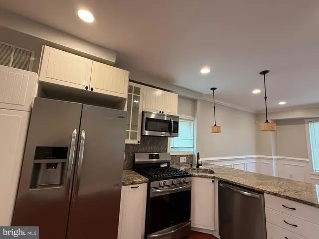 a kitchen with granite countertop a refrigerator stove and microwave