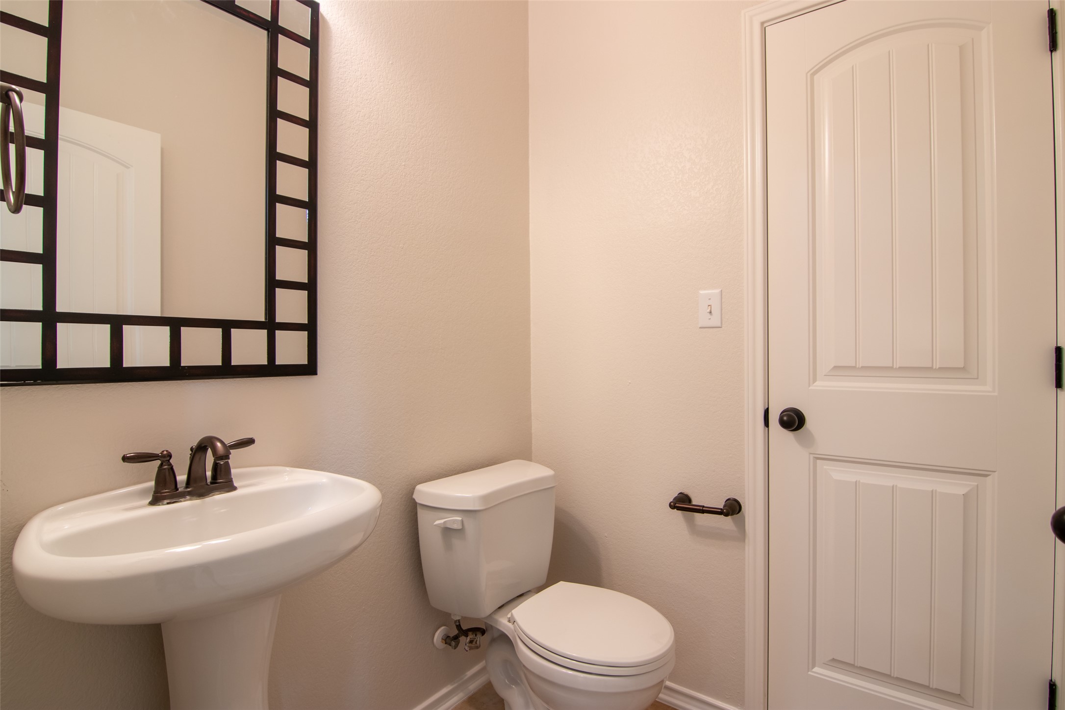 12104 Broten Street Austin, TX 78748 - Photo 14 of 32 A well-appointed powder room features a pedestal sink, toilet, and an elegantly framed mirror.