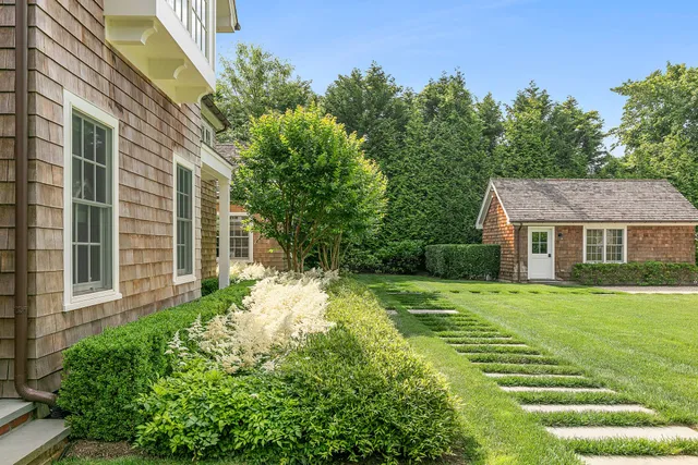 a view of a big yard with plants and large trees