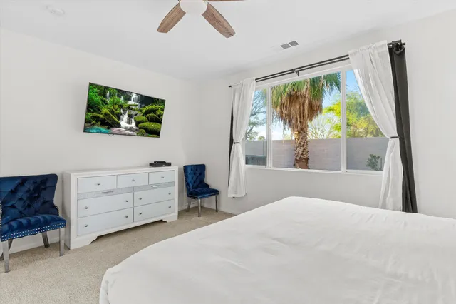 a bedroom with a bed and a flat tv screen on dresser