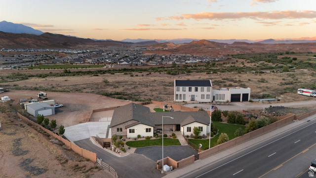 2591 East Washington Dam Road Washington, UT 84780 - Photo 63 of 67 Expansive property featuring a single-story residence with a stone and stucco exterior, a two-story residence with a modern white facade and attached garages, a paved driveway, and established green lawn areas