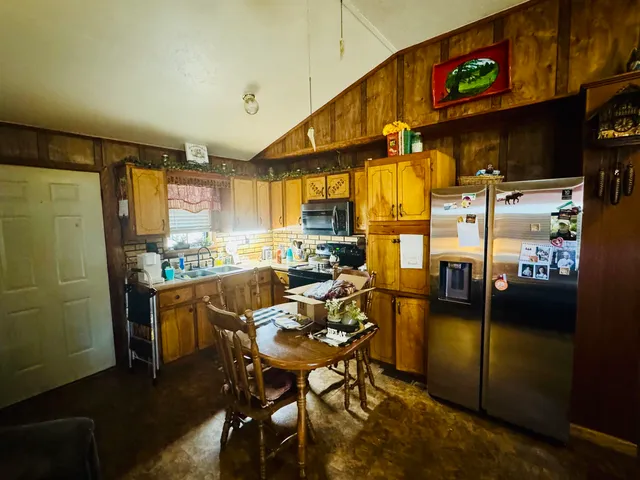 a kitchen with stainless steel appliances kitchen island granite countertop dining table chair and a refrigerator