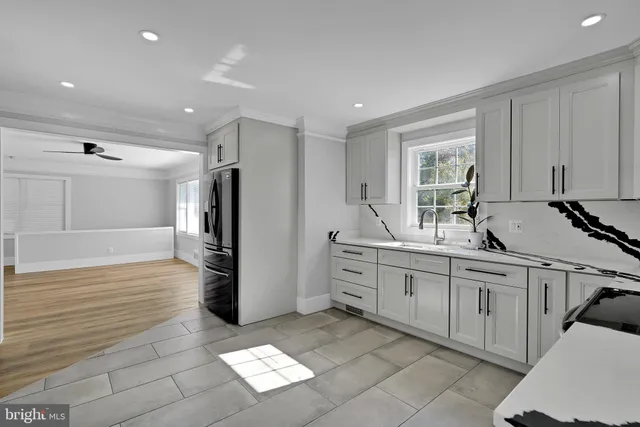 a large white kitchen with stainless steel appliances granite countertop a refrigerator and a sink