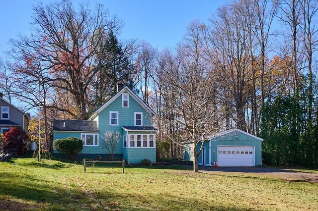 a front view of a house with a garden and tree