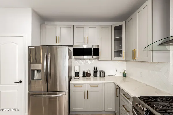 a kitchen with stainless steel appliances a refrigerator a sink and white cabinets