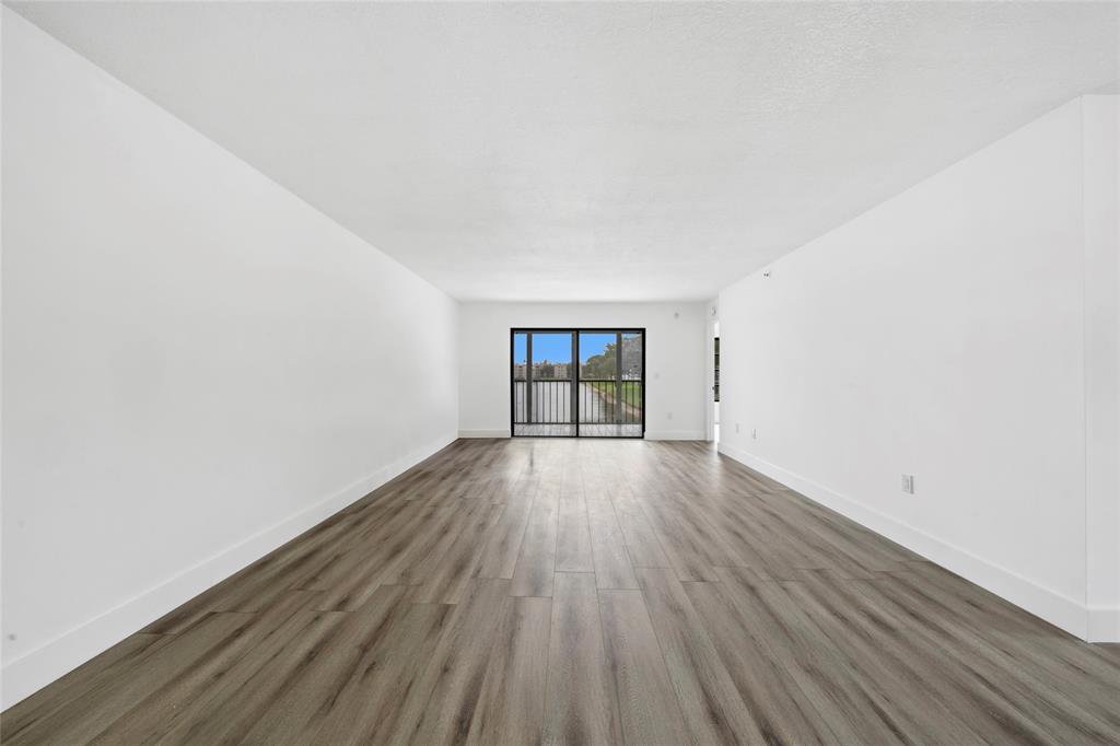 6269 Pointe Regal Circle, Unit 210 Delray Beach, FL 33484 - Photo 14 of 29 an empty room with wooden floor and windows