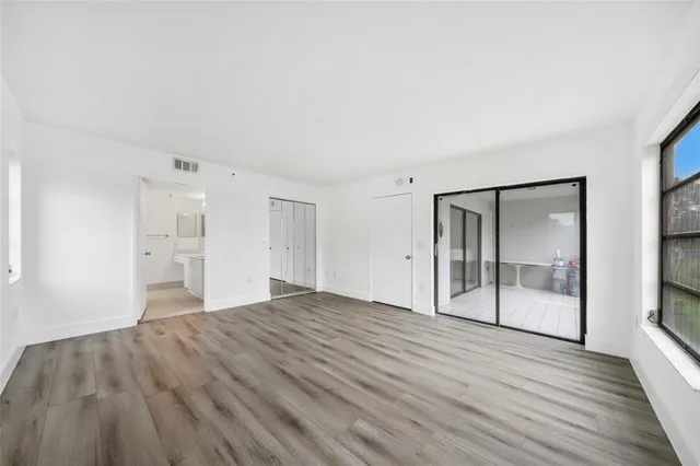 a view of empty room with wooden floor and fan