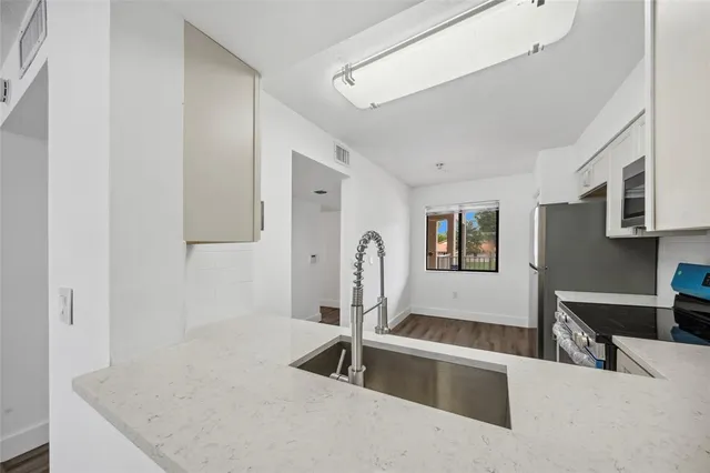 a indoor kitchen with stainless steel appliances granite countertop a sink and a refrigerator