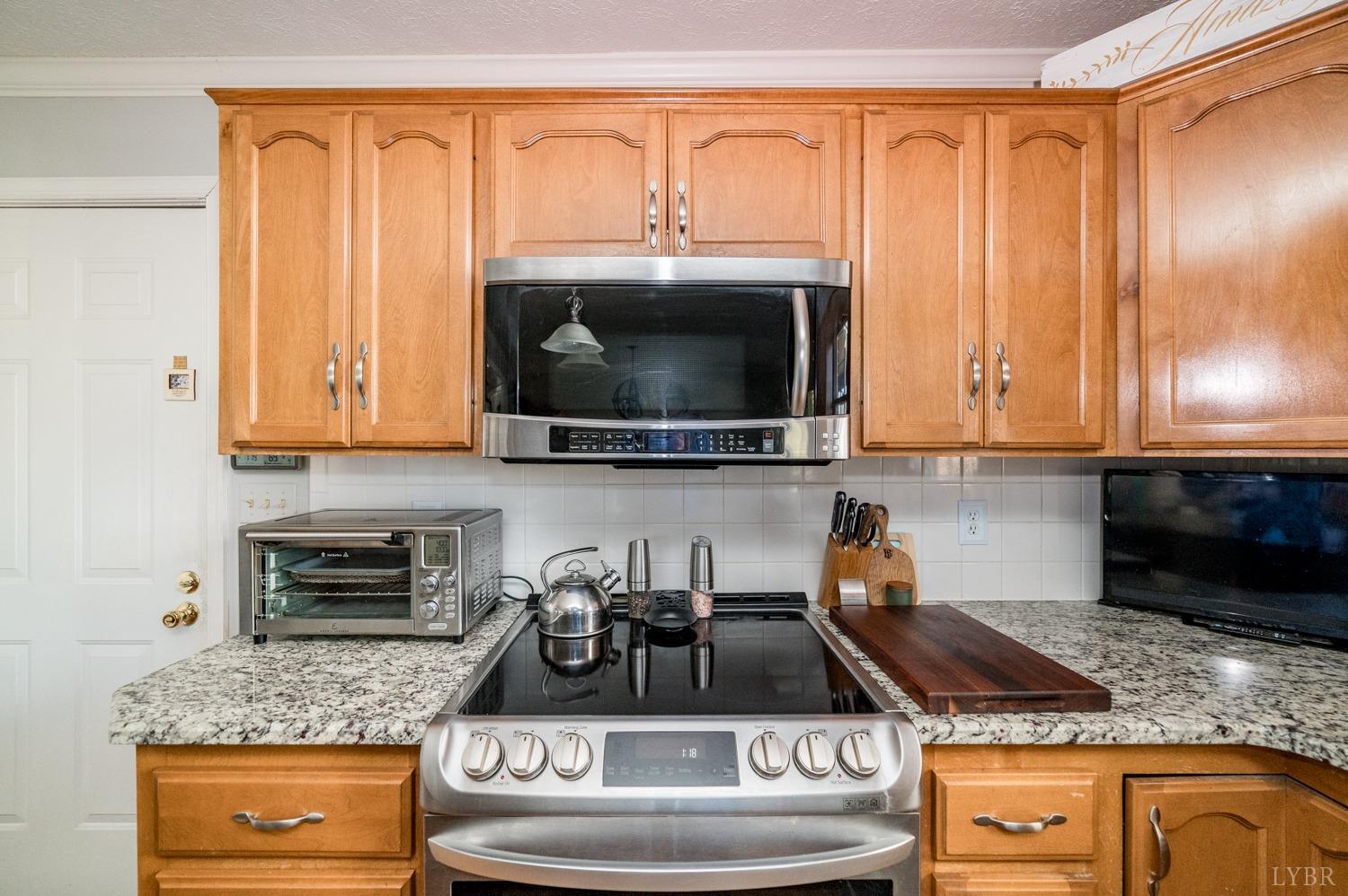 325 Longhill Road Goode, VA 24556 - Photo 25 of 71 a kitchen with granite countertop a stove and a microwave