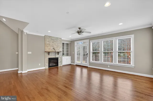 a view of an empty room with window and wooden floor