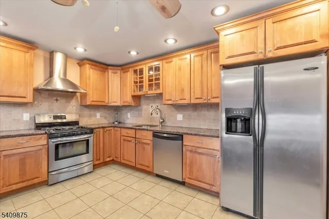 a kitchen with stainless steel appliances granite countertop a refrigerator a sink a stove and oven