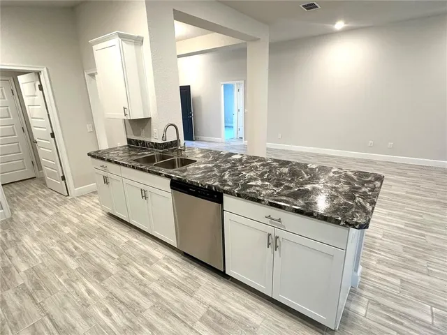 a kitchen with granite countertop a sink and cabinets