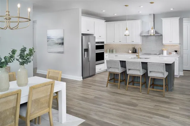 a kitchen with stainless steel appliances a dining table chairs and wooden floor