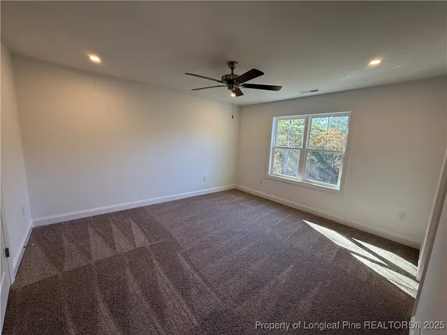 an empty room with windows and ceiling fan