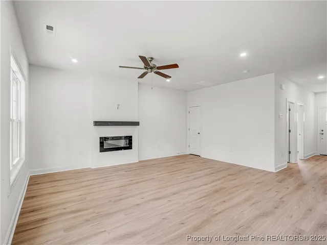 a view of empty room with wooden floor and ceiling fan