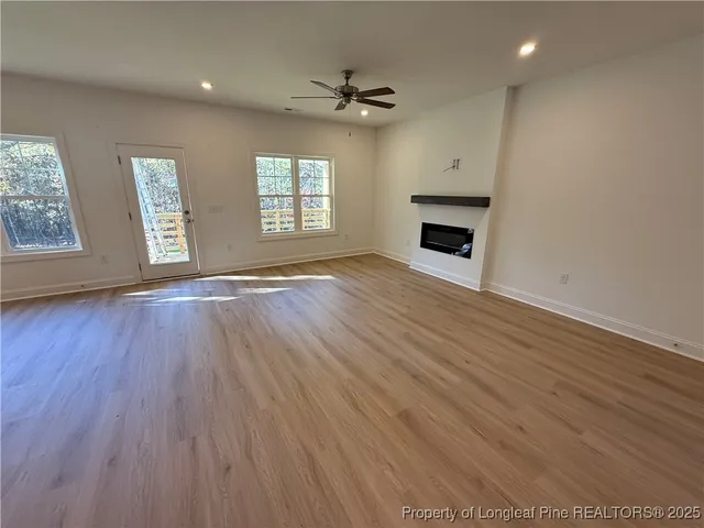 an empty room with wooden floor a ceiling fan and windows