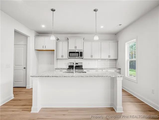 a kitchen with kitchen island granite countertop a sink cabinets and wooden floor