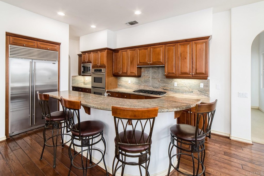 6237 Paseo Privado Carlsbad, CA 92009 - Photo 4 of 29 a kitchen with stainless steel appliances granite countertop a stove a refrigerator a kitchen island and chairs in it