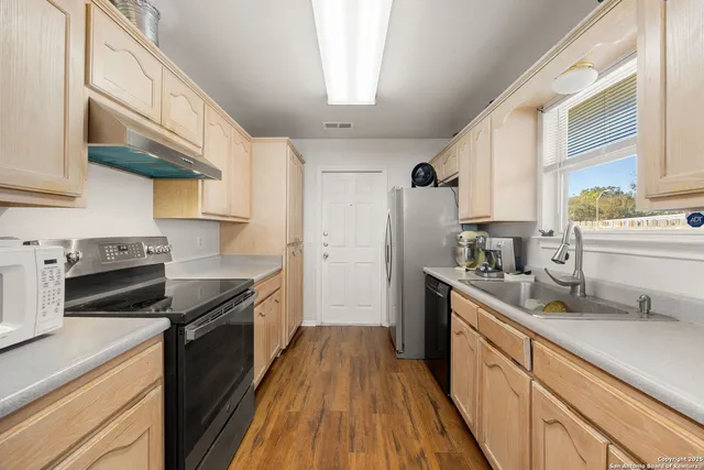 a kitchen with stainless steel appliances granite countertop hardwood floor sink stove and refrigerator