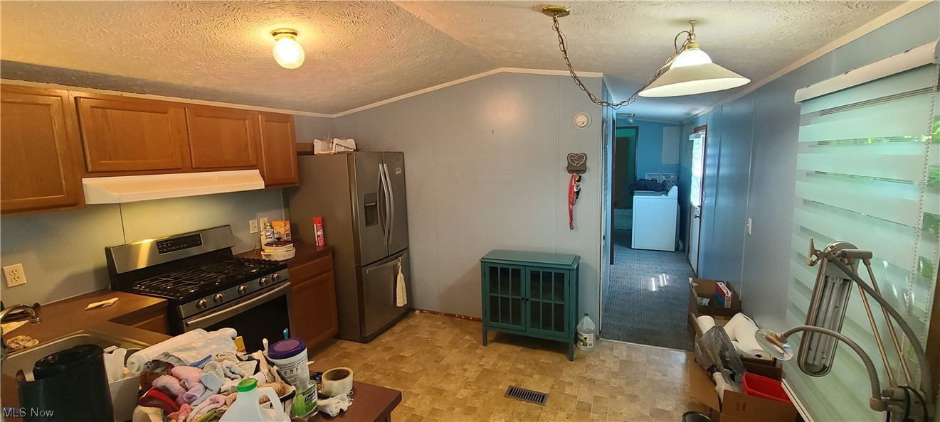 5974 Cleveland Road, Unit 19 Wooster, OH 44691 - Photo 3 of 17 Kitchen with stainless steel appliances, a textured ceiling, decorative light fixtures, lofted ceiling, washer / clothes dryer, ornamental molding, and light tile floors