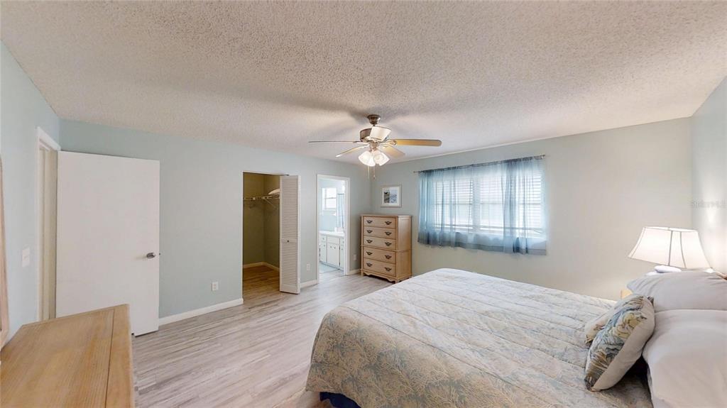 8678 Southwest 95 Street, Unit B Ocala, FL 34481 - Photo 16 of 22 a spacious bedroom with a bed and a chandelier