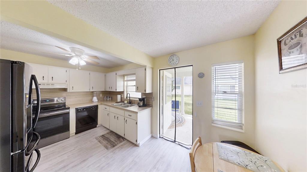 8678 Southwest 95 Street, Unit B Ocala, FL 34481 - Photo 8 of 22 a kitchen with stainless steel appliances granite countertop a stove a sink dishwasher a refrigerator and white cabinets with wooden floor