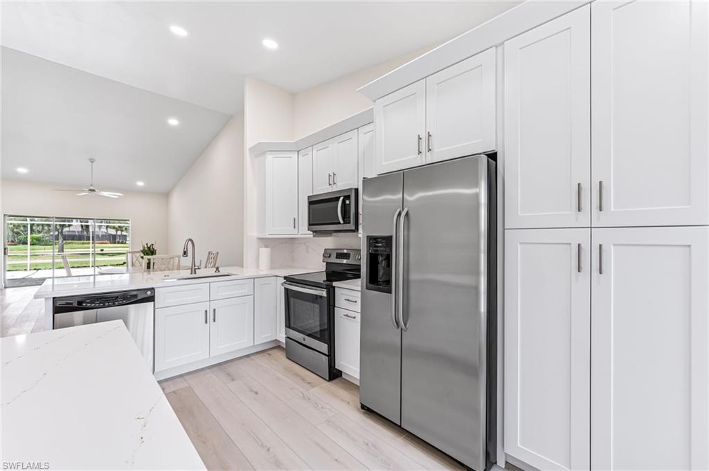 8562 Mustang Drive, Unit 31 Naples, FL 34113 - Photo 5 of 44 Kitchen featuring light stone counters, a sink, light wood-style floors, appliances with stainless steel finishes, and white cabinetry