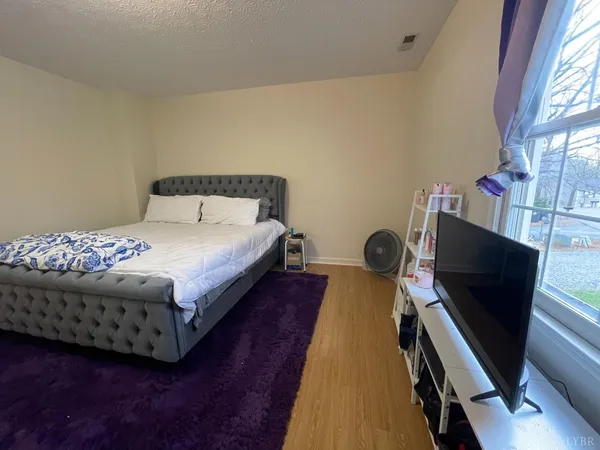 a bed sitting in a bedroom next to a window with wooden floor