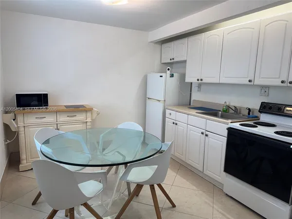 a kitchen with stainless steel appliances granite countertop a sink a stove a refrigerator and white table with chairs