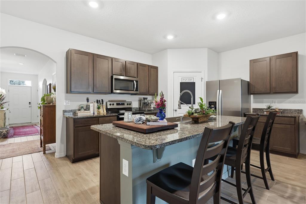 8261 Southwest 60th Avenue Gainesville, FL 32608 - Photo 28 of 34 a kitchen with stainless steel appliances granite countertop a stove top oven a refrigerator a sink and a dining table with chairs