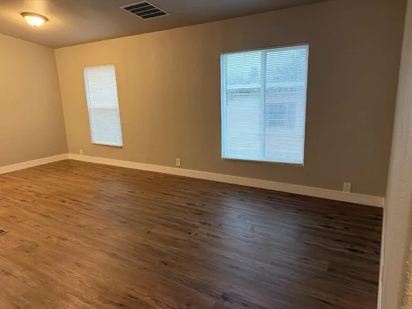an empty room with wooden floor and windows