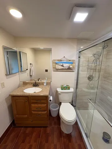 a bathroom with a granite countertop toilet sink and mirror