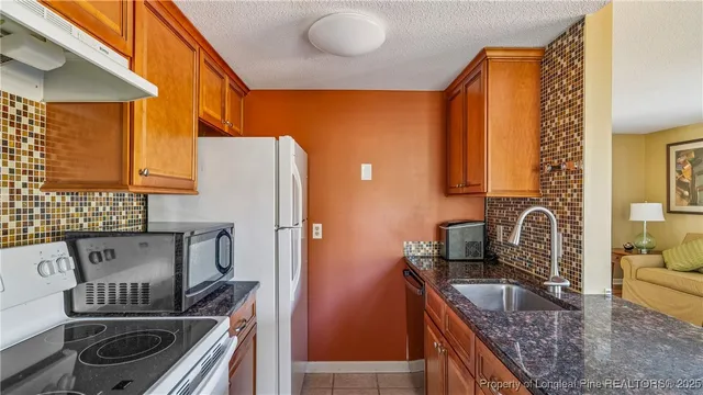 a kitchen with granite countertop a sink a stove and wooden cabinets