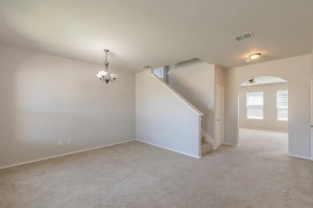 an empty room with a chandelier fan and windows