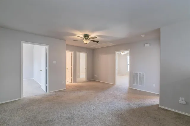 a view of an empty room with a chandelier fan