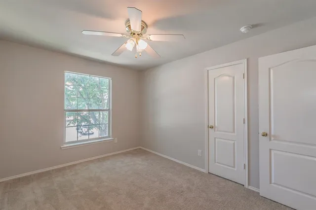 an empty room with windows and fan