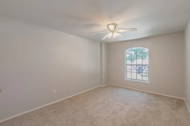 an empty room with windows and ceiling fan