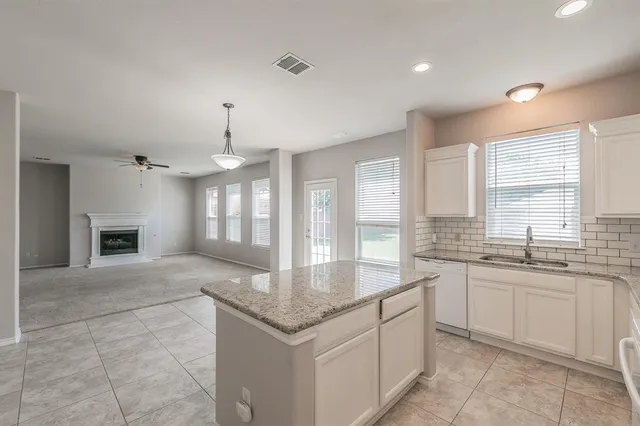 a large kitchen with granite countertop a sink and dishwasher a oven with white cabinets