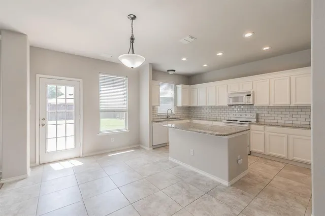 a large kitchen with granite countertop white cabinets and white appliances