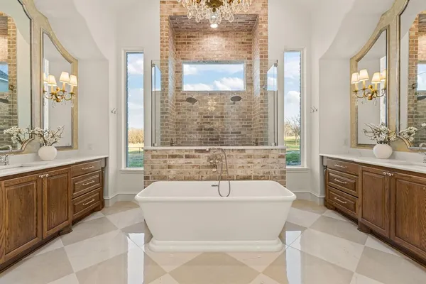 a spacious bathroom with a sink a mirror a bathtub and next to a window