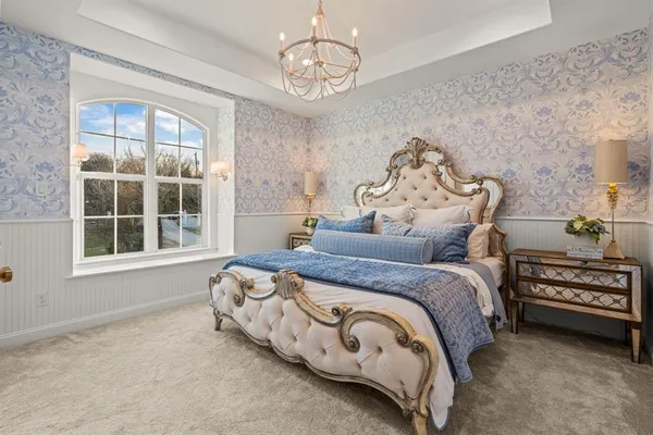 a spacious bedroom with a bed and a chandelier