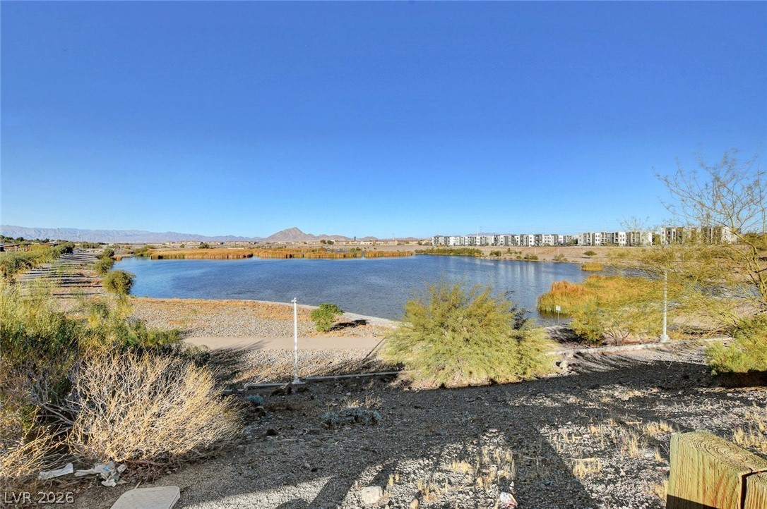 48 Jasmine Point Street Henderson, NV 89074 - Photo 12 of 62 A tranquil lake view unfolds, framed by distant mountains and a serene, clear blue sky.