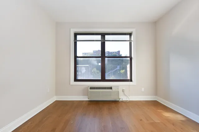 an empty room with wooden floor and a window