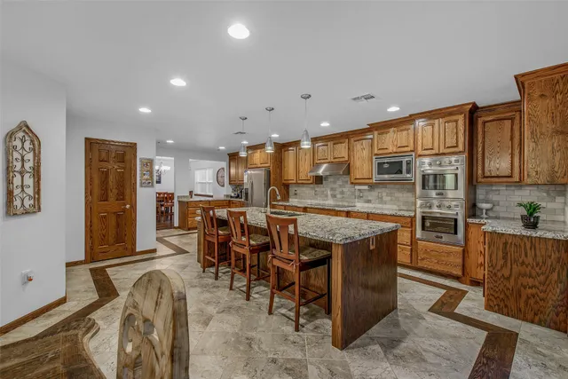 a kitchen with stainless steel appliances granite countertop a table chairs sink and cabinets