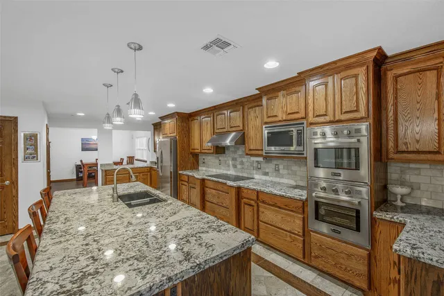 a kitchen with stainless steel appliances granite countertop a sink stove and refrigerator