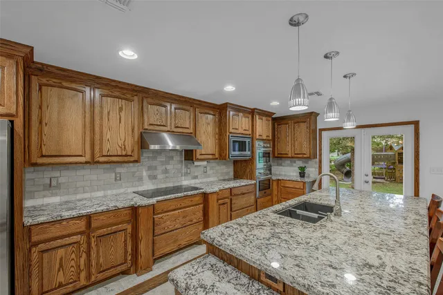 a kitchen with stainless steel appliances granite countertop sink stove and refrigerator