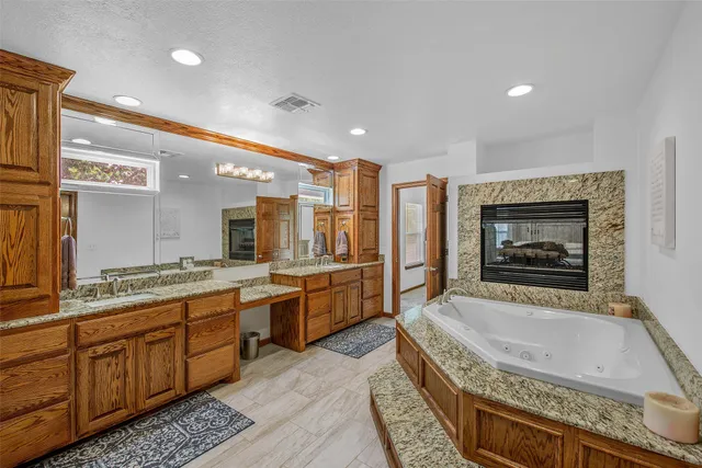 a spacious bathroom with a granite countertop tub a sink and a large mirror