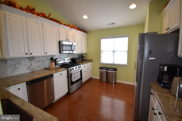 a kitchen with stainless steel appliances granite countertop a stove a sink and a refrigerator